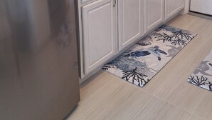 Una cocina con armarios blancos, un refrigerador de acero inoxidable, un fregadero y un cartel que dice 'Bon Appetit'.