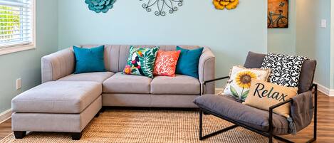 A living room with a sectional sofa, a chair, and decorative wall art.