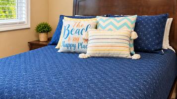 A bedroom with a bed, a headboard, a window, a wall-mounted painting, and a bedside table with a plant.