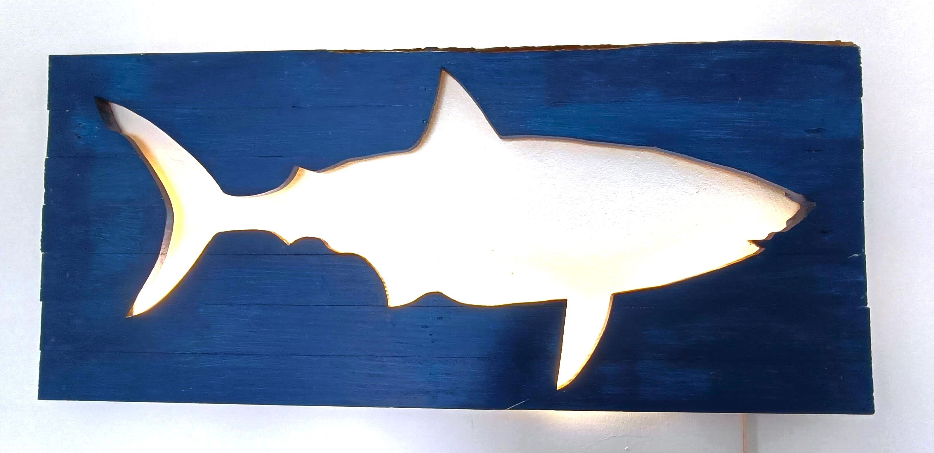 Eine Haifischsilhouette vor blauem Hintergrund.