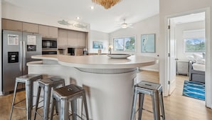A modern kitchen with a central island, stainless steel appliances, and a decorative fish wall art. - Pet-Friendly, Close to beach access & town, Large - 2100 sq ft! Afternoon Delight! (Folly Beach)