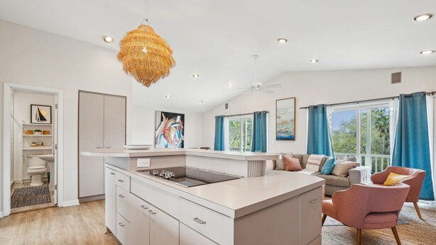 A modern kitchen with a central island, white cabinetry, and a hanging light fixture. - Pet-Friendly, Close to beach access & town, Large - 2100 sq ft! Afternoon Delight! (Folly Beach)