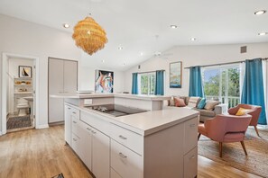 A modern kitchen with a central island, white cabinetry, and a hanging light fixture. - Pet-Friendly, Close to beach access & town, Large - 2100 sq ft! Afternoon Delight! (Folly Beach)