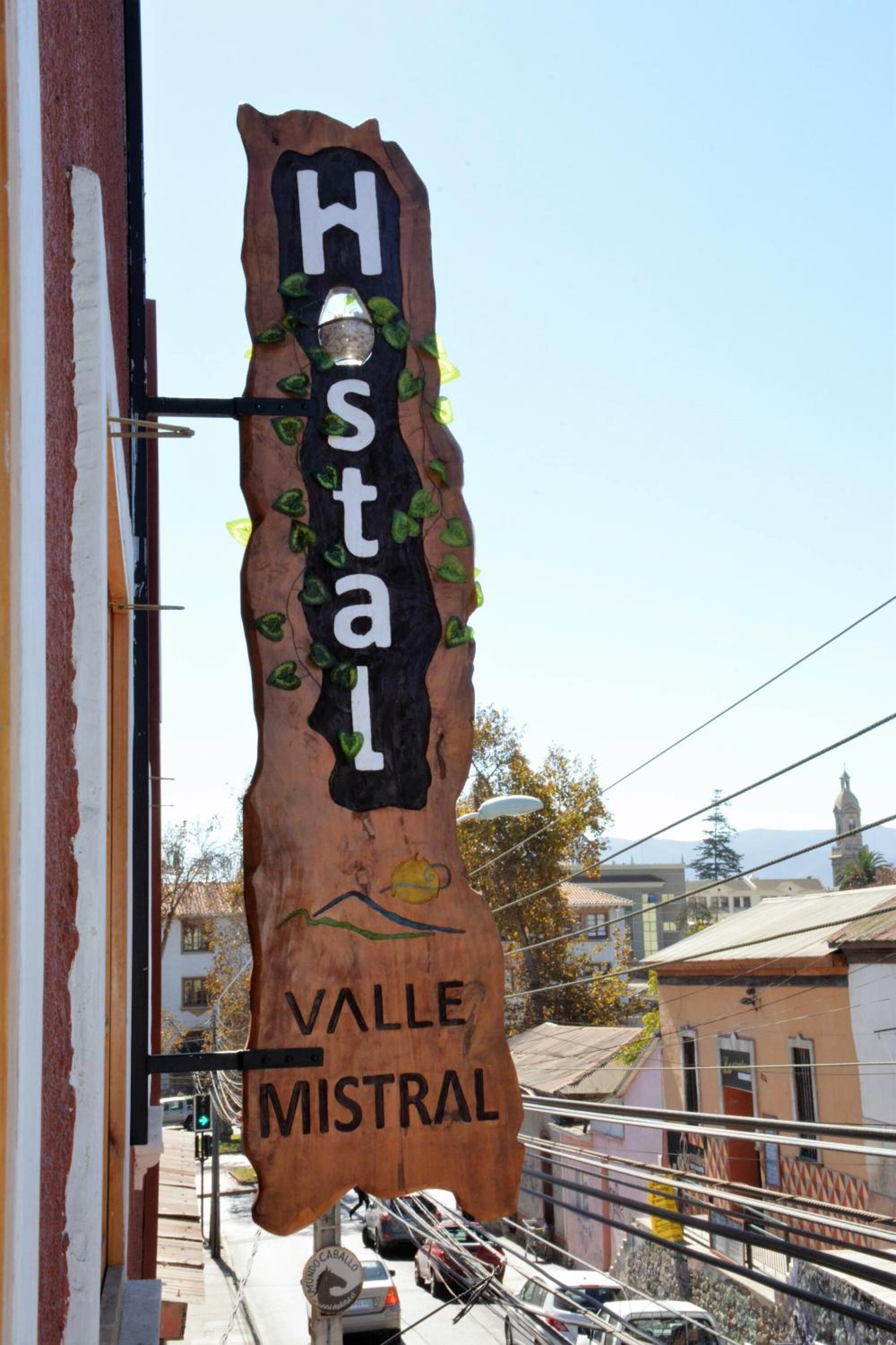 Ein Holzschild mit der Aufschrift "Hostal" und "Valle Mistral", das ein Hotel oder eine Unterkunft anzeigt.