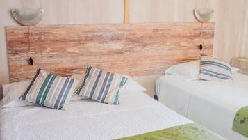 A room with a rustic wooden headboard, two beds with striped pillows, and a green throw blanket.
