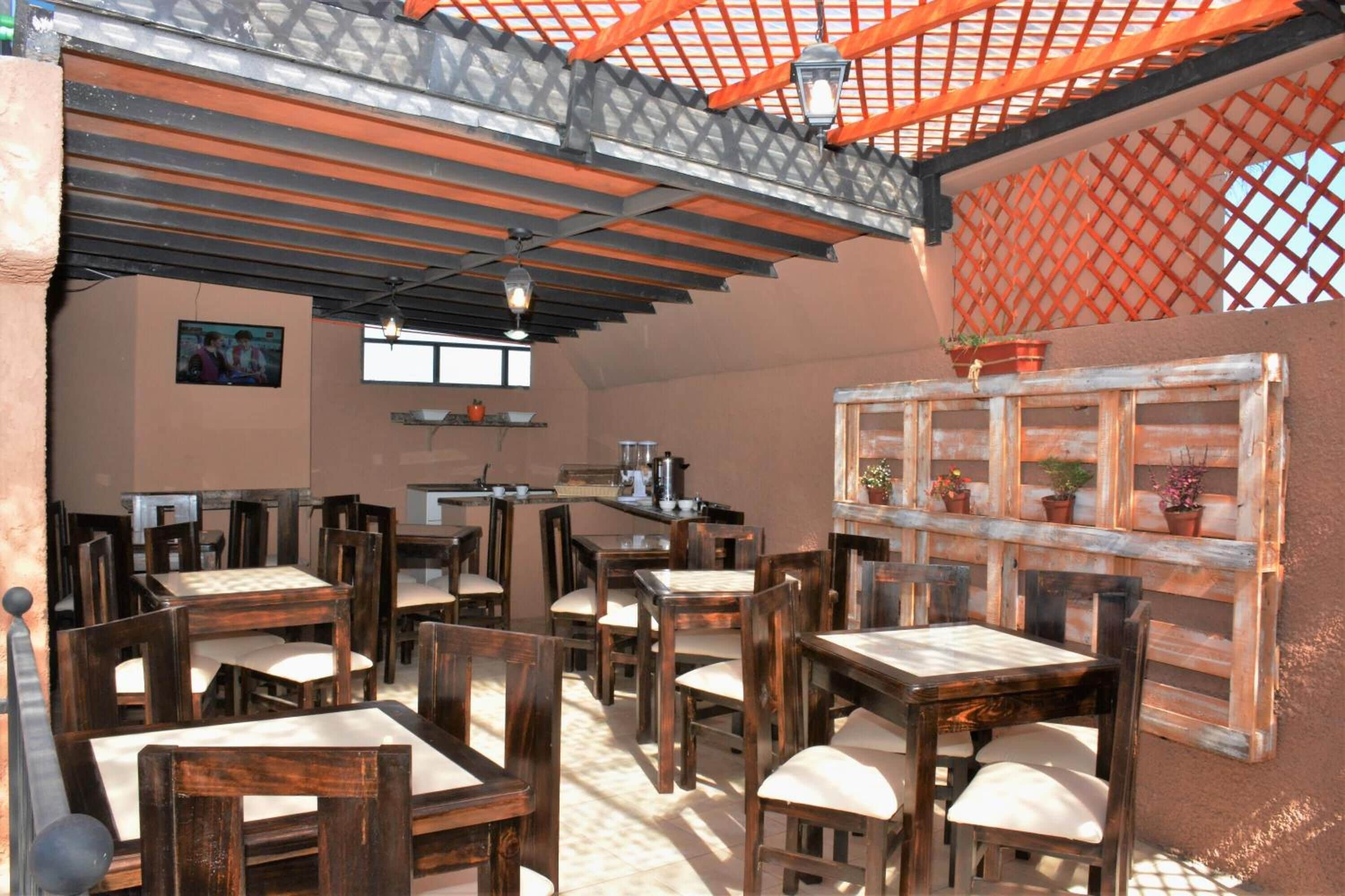 A rustic dining area with wooden tables and chairs, a bar area, and a lattice window structure.