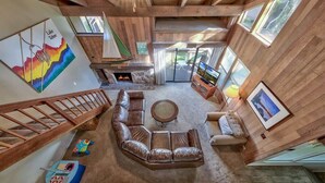 A spacious living area with a fireplace, leather sofa, and a colorful mural.