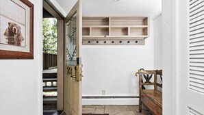 Un pasillo con un banco de madera, un cuadro enmarco y un estante empotrado con varios compartimentos.