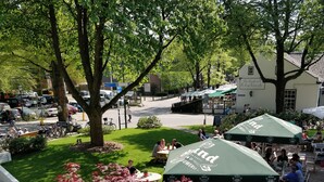An outdoor seating area with tables and chairs, surrounded by greenery and trees. - De Kastanjehof (Lage Vuursche)
