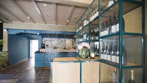 A bar area with a counter, shelves of bottles, and a vase with flowers. - De Kastanjehof (Lage Vuursche)