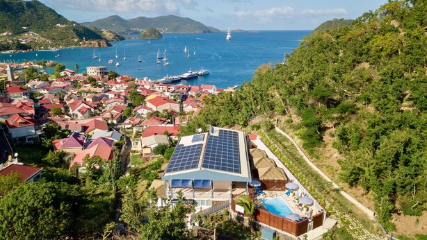 Ein Küstenwohngebiet mit Häusern, einem Schwimmbad und Solaranlagen auf einem Gebäude.