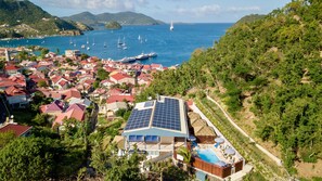 Un quartier résidentiel situé sur la côte, avec des maisons, une piscine et des panneaux solaires installés sur un bâtiment.