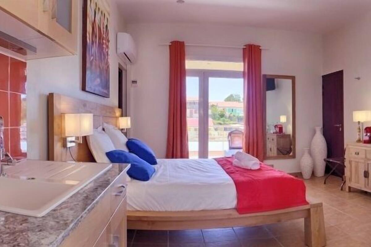Une chambre d’hôtel avec un lit, une salle de bain comprenant un lavabo et une douche, et donnant sur l’extérieur.