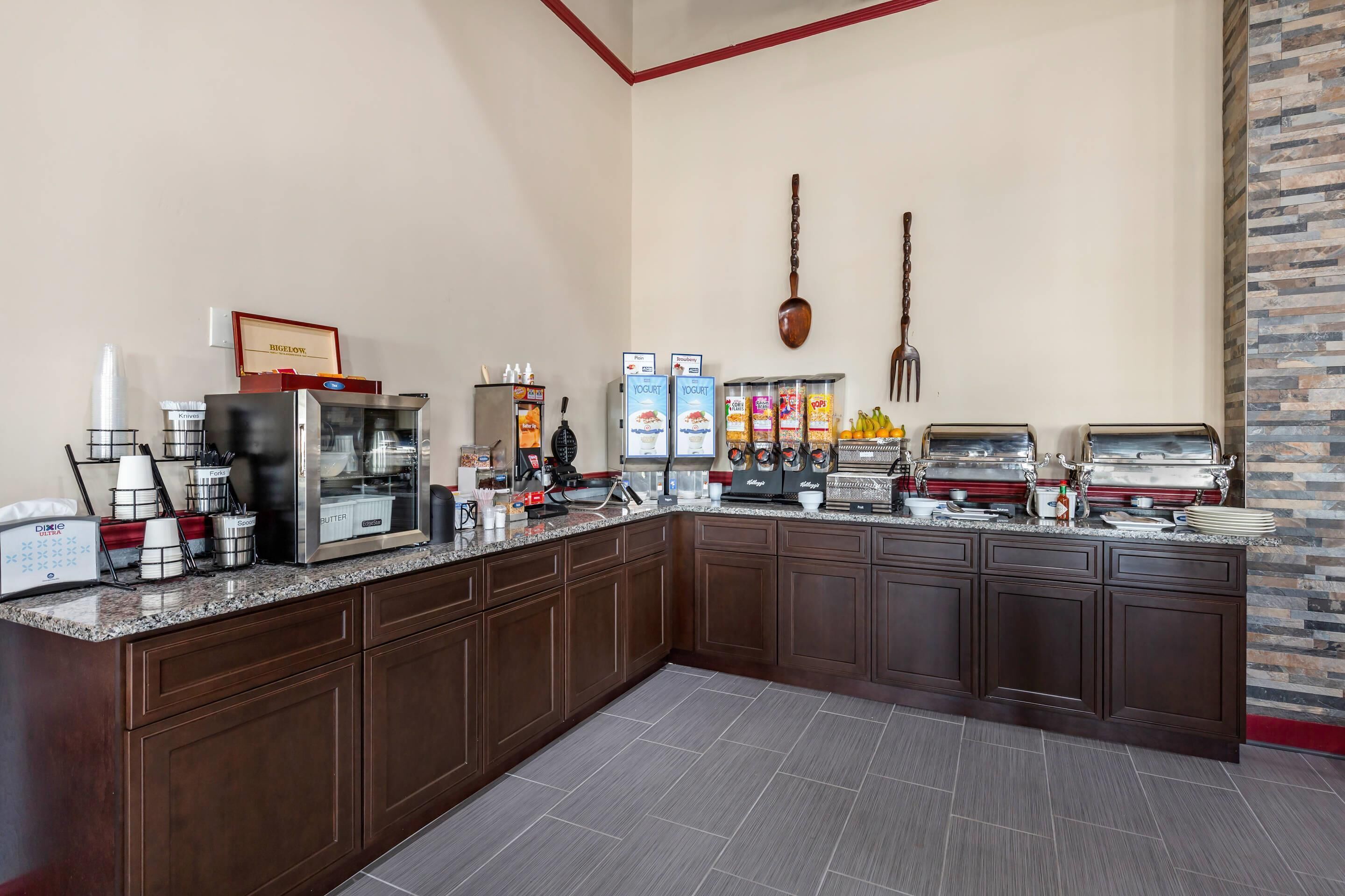 A breakfast bar with coffee machines, yogurt dispensers, and a variety of food items.