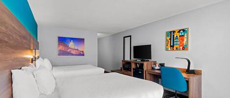 A hotel room with a bed, a desk, a chair, a television, and artwork on the walls.