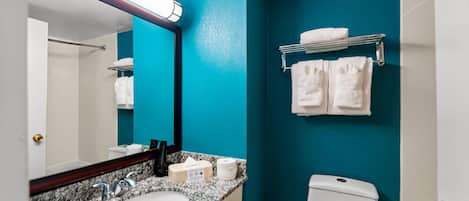 A bathroom with a white sink, a mirror, a towel rack, and a toilet.