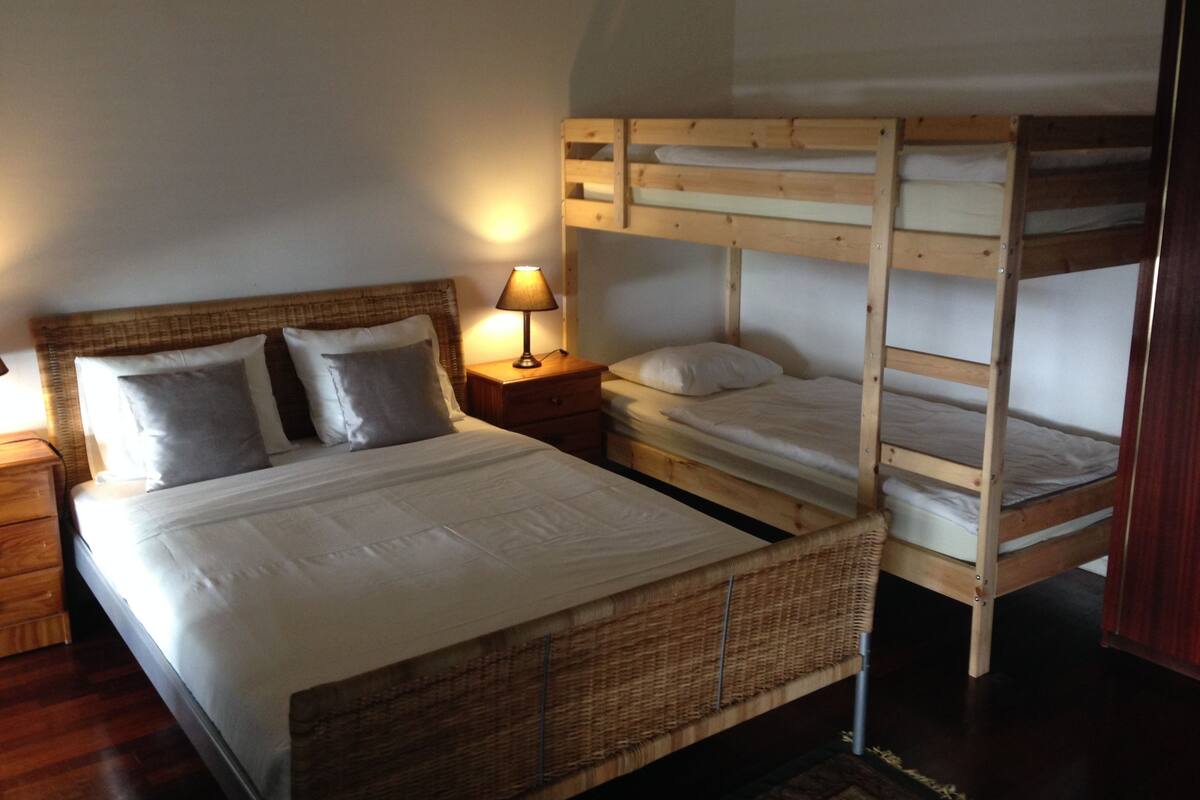 Una cama litera con cabecera de madera y una mesita de noche con lámpara.