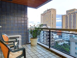 En balkon med stol, lille bord og en potteplante.