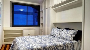 Una camera da letto con un letto, spazio contenitivo integrato, una finestra con tende e vista all'esterno.