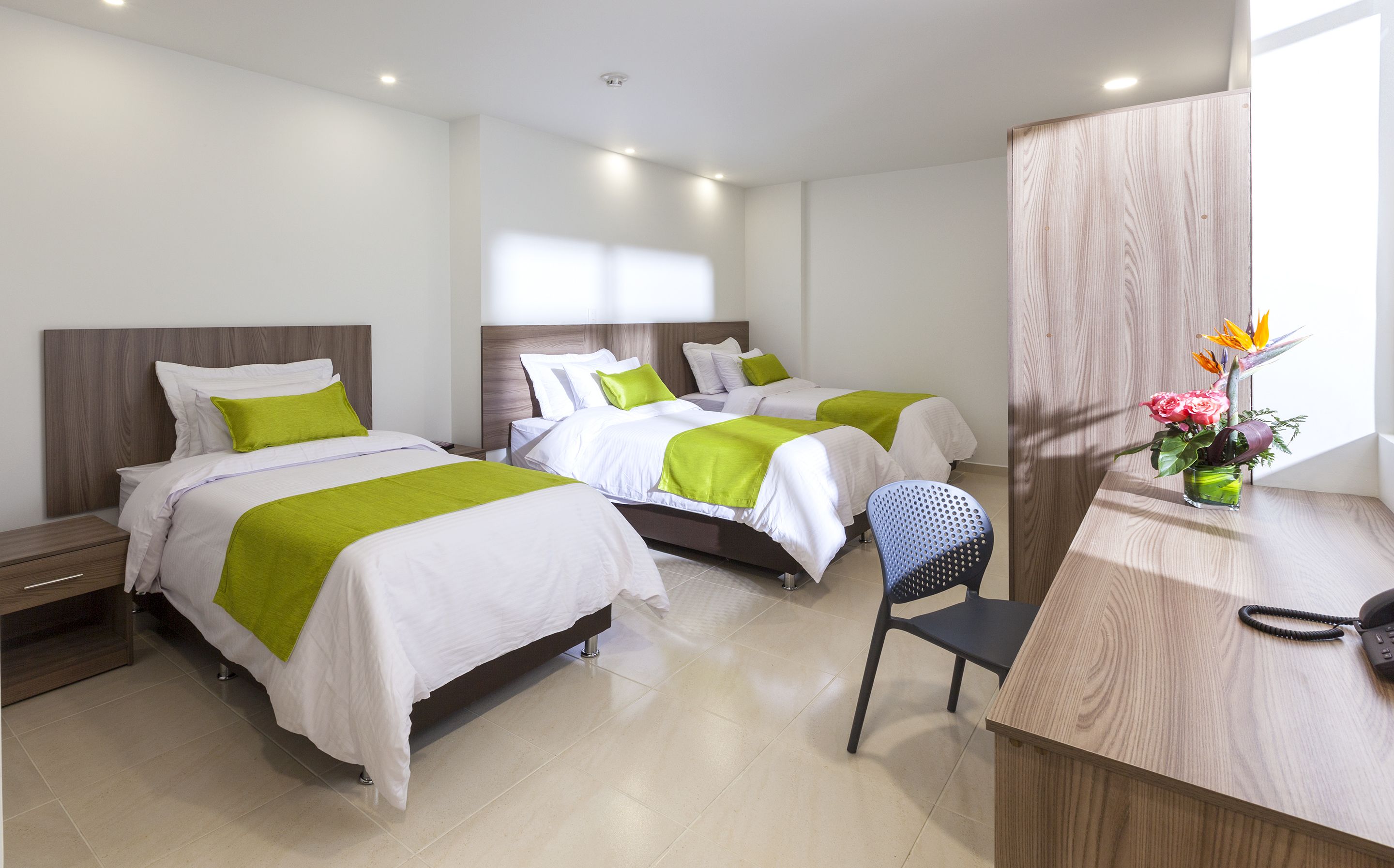 A hotel room with two beds, a desk, and a chair.