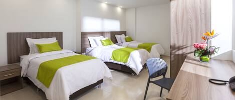A hotel room with two beds, a desk, and a chair.