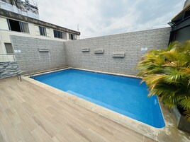 Una piscina al aire libre, sillones reclinables de piscina