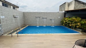 A swimming pool with a stone wall and a metal chair. - Torca Hotel (Cali)