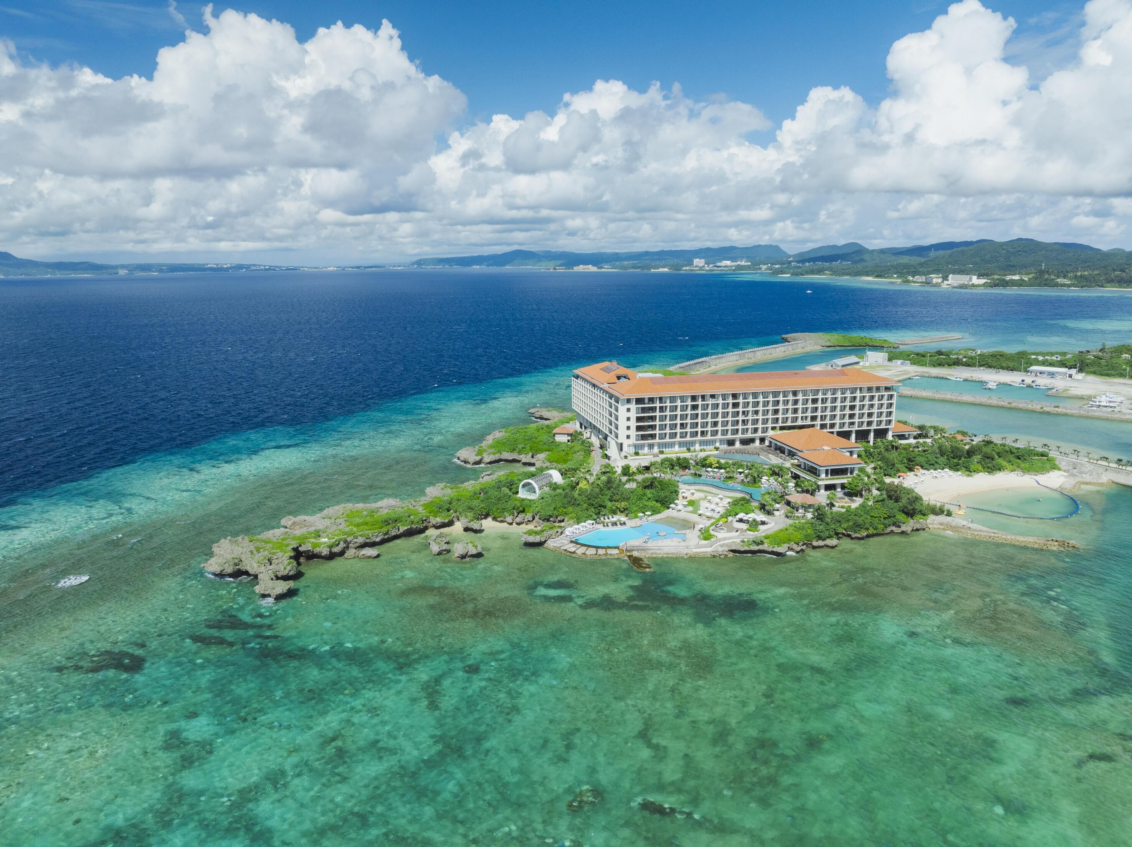 Un hotel resort en una isla tropical con aguas cristalinas, piscina y playa.