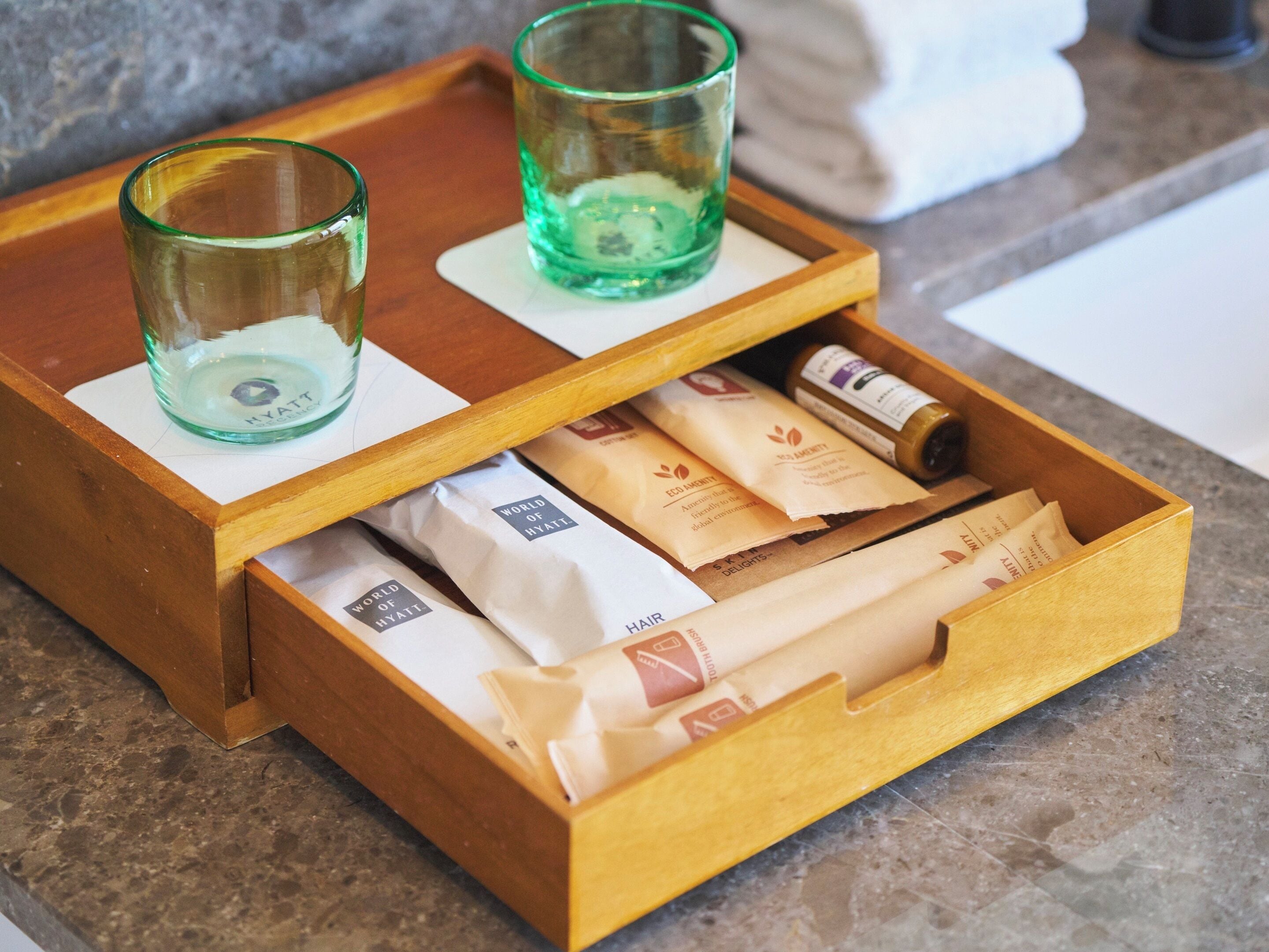 A wooden tray with two glasses and several toiletry bags.