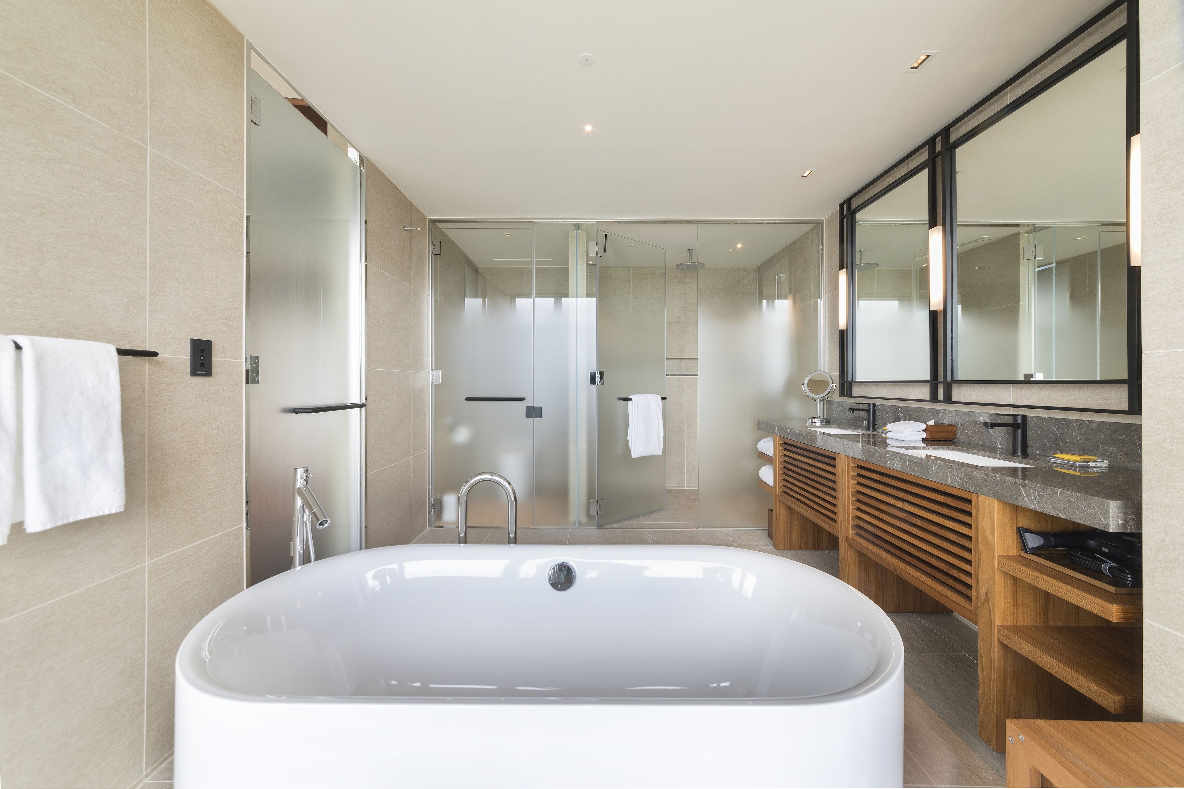 A modern bathroom with a large freestanding bathtub, a glass-enclosed shower, and a vanity with a mirror.