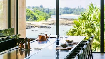 Una mesa de comedor con vistas a la playa y al follaje.