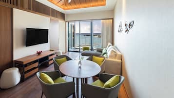 A modern living room with a large TV, a round table, and comfortable seating.