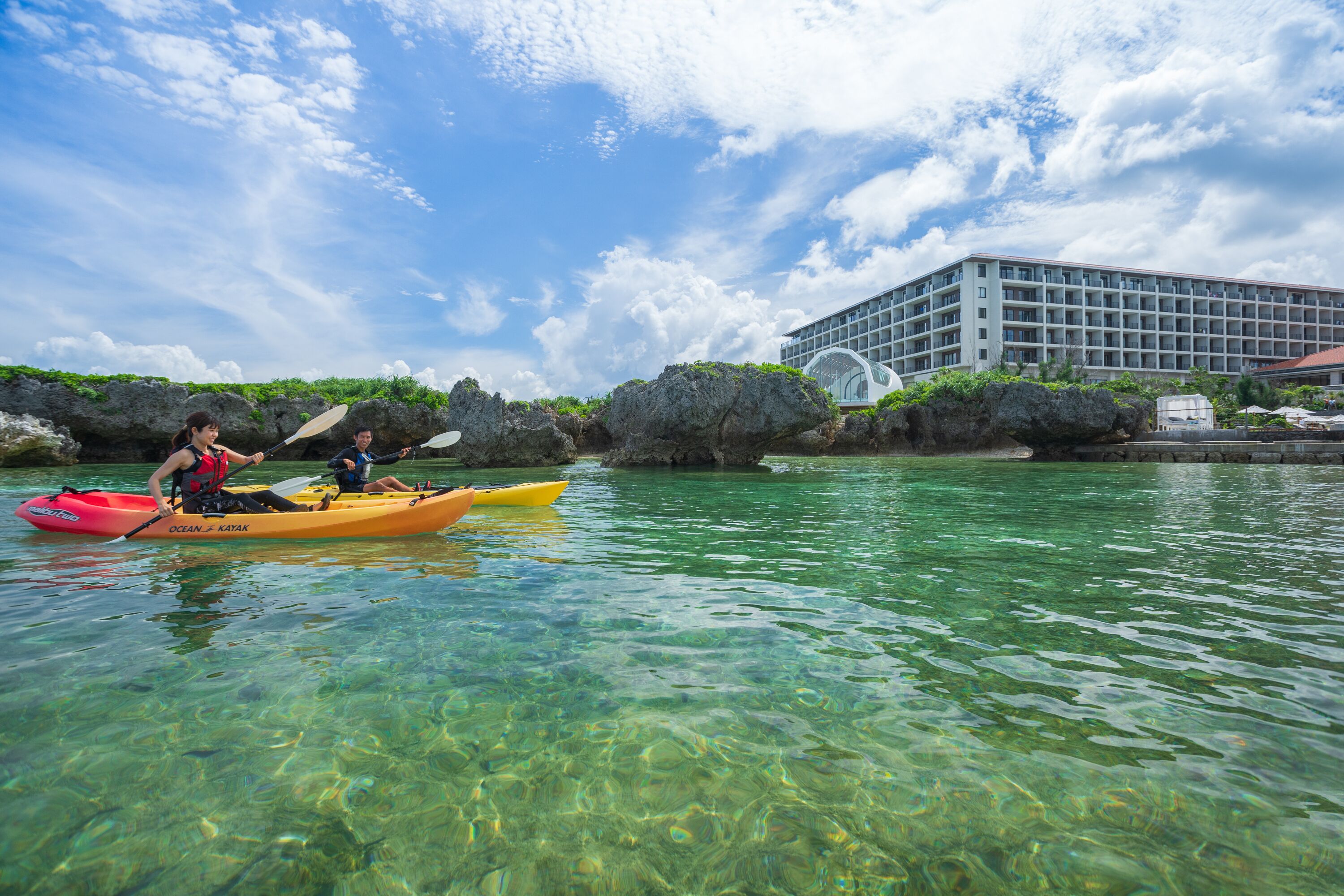 Una orilla despejada con kayak, un edificio de diseño moderno y formaciones rocosas.