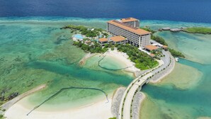 Vue aérienne d’un complexe hôtelier comprenant un grand bâtiment, plusieurs piscines et une plage.