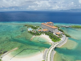 Vista aérea de un resort con un edificio grande, varias piscinas y una playa.