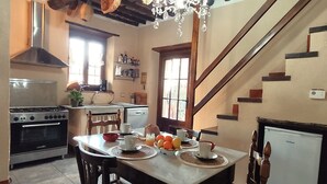 A kitchen with a dining table set for four, a refrigerator, and a stove. - Characteristic tuscan rustic (Camaiore)