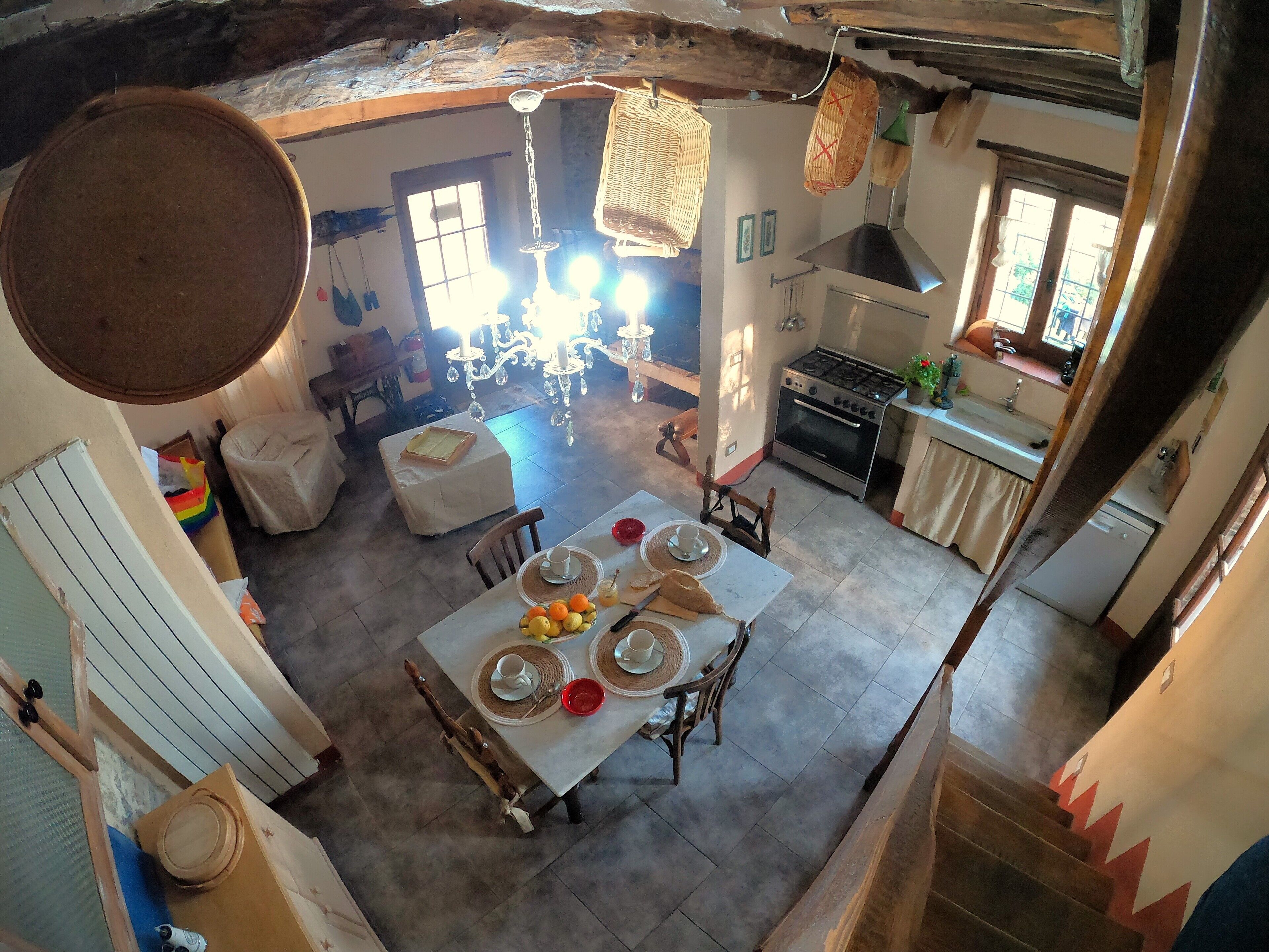 A dining area with a table set for four, a chandelier, and a kitchen in the background.