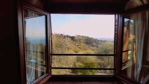 A room with a large window offering a view of a hilly landscape. - Characteristic tuscan rustic (Camaiore)