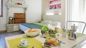 A cozy bedroom with a bed, a small fireplace, a dining table with breakfast items, and a painting on the wall. - Beautiful apartment in Longare -VI- with WiFi (Longare -VI-)