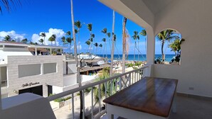 Un balcone con vista sulla spiaggia, palme e un edificio con la scritta "Villa Paradiso".