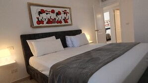 Una camera da letto con un letto, lampade sui comodini, una testiera e un quadro appeso al muro.