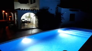 A swimming pool at night with a patio area visible in the background. - Villa in L'Escala, Costa Brava, Spain. - Private Pool (L'Escala)