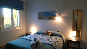 A bedroom with a bed, a nightstand, a wall-mounted lamp, and a window. - Villa in L'Escala, Costa Brava, Spain. - Private Pool (L'Escala)