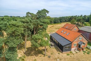 A modern house with a sloped roof, large windows, and a patio area.