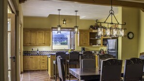 A kitchen with wooden cabinets, a dining table with chairs, and pendant lights. - AV149-Loreto Bay-Luxury Private Villa with Pool (Loreto)