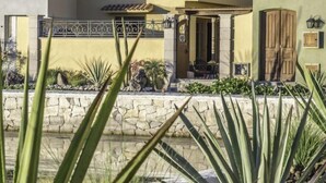A modern building with multiple balconies and a stone wall in the foreground. - AV149-Loreto Bay-Luxury Private Villa with Pool (Loreto)