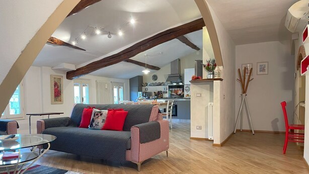 A spacious living area with a sofa, a coffee table, and a kitchen in the background. - Luminosa e caratteristica mansarda con affacci su Villa Bottini in centro conA/C (Lucca)