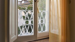 A window with a white frame and a view of a balcony with a white railing. - Luminosa e caratteristica mansarda con affacci su Villa Bottini in centro conA/C (Lucca)