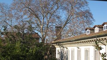 A building with a white facade, multiple windows with shutters, and a tiled roof.