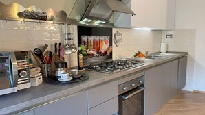 A modern kitchen with a gas stove, oven, and stainless steel appliances. - Luminosa e caratteristica mansarda con affacci su Villa Bottini in centro conA/C (Lucca)